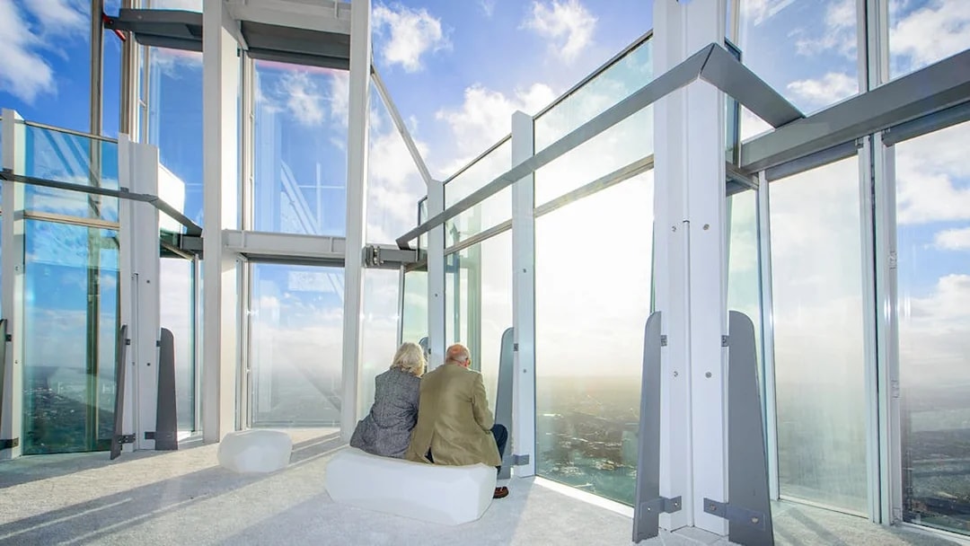 Old couple enjoying city view from The Shard's observation deck in London.