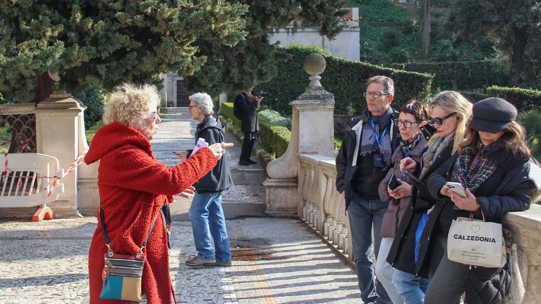 Tour guide explaining to visitors at Tivoli Villa d'Este gardens.