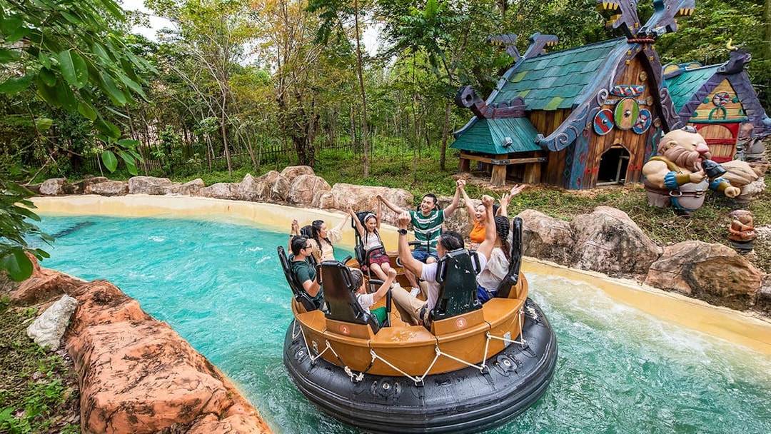 Group enjoying water ride at VinWonders Phu Quoc with themed buildings in background.