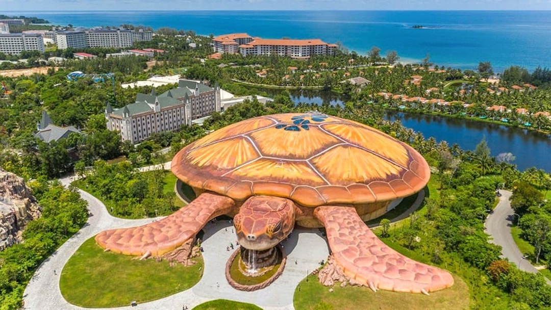 Aerial view of turtle-shaped building at VinWonders, Phu Quoc, with ocean in background.