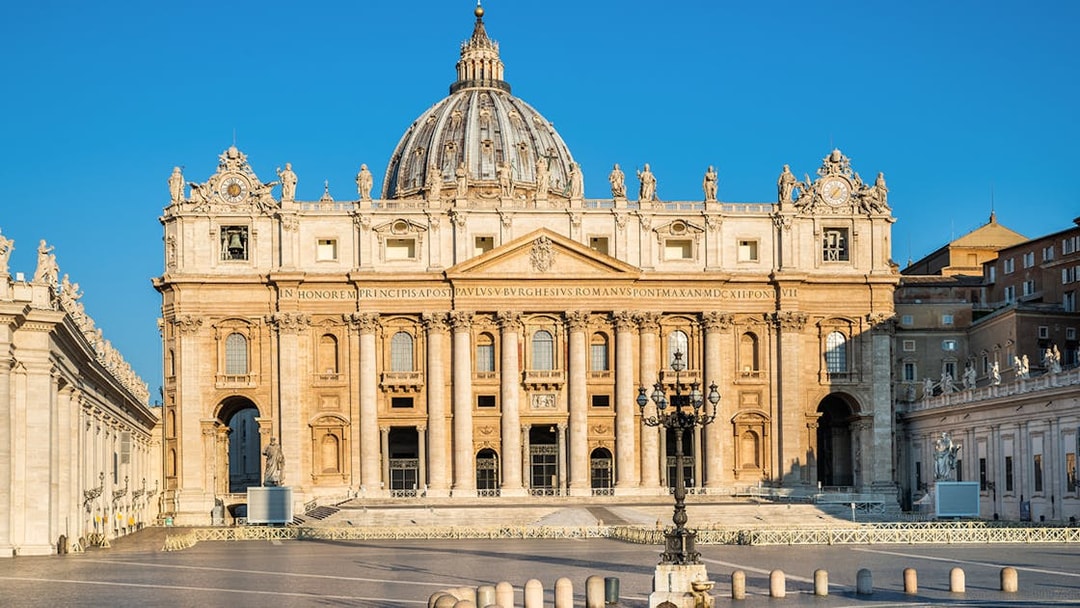 St. Peter's Basilica facade in Vatican City under clear blue sky.
