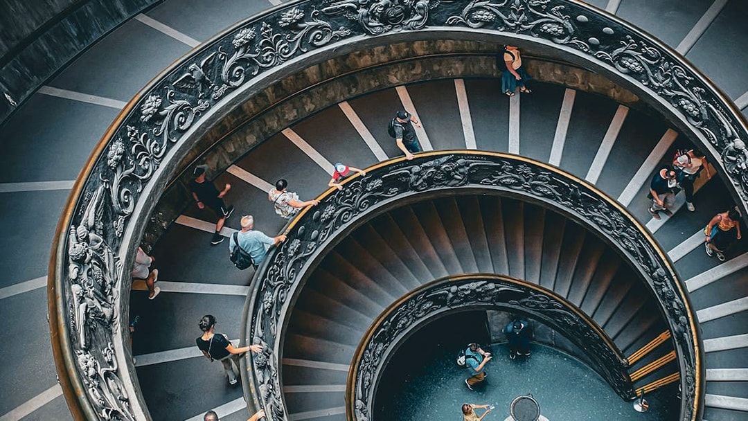 Vatican Museum spiral staircase with visitors, part of private tour experience.