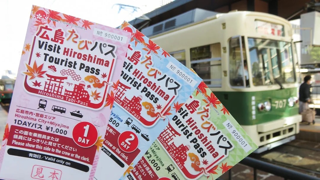 Hiroshima Tourist Passes held in front of a tram in Hiroshima, Japan.