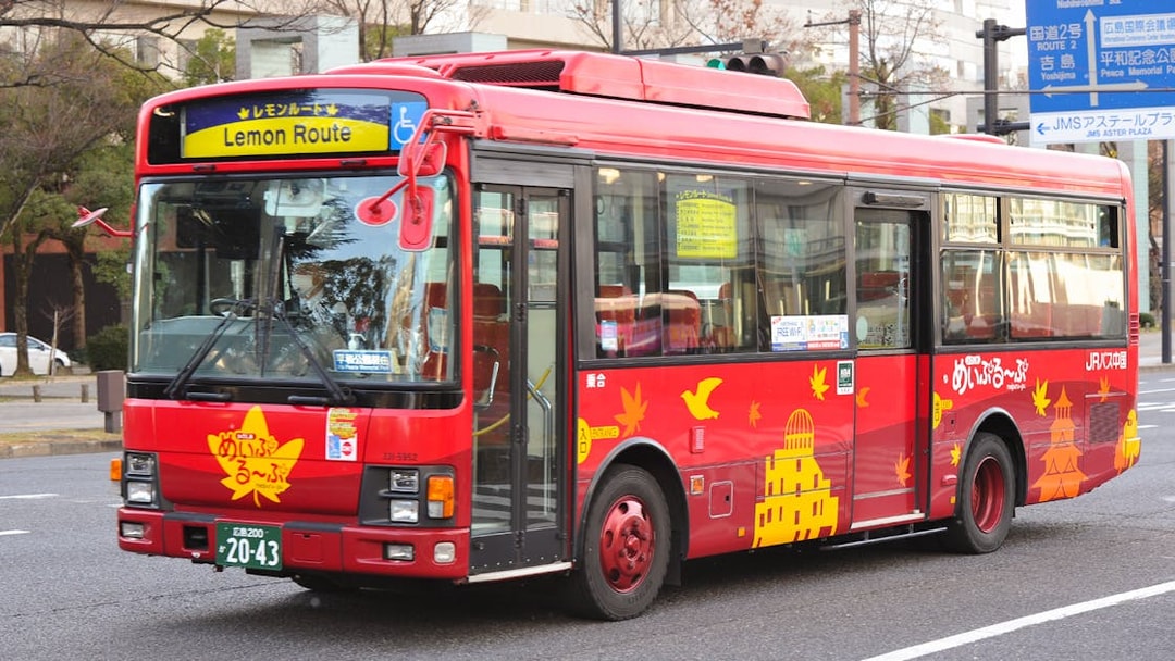Red Hiroshima tourist bus on Lemon Route with city landmarks depicted.