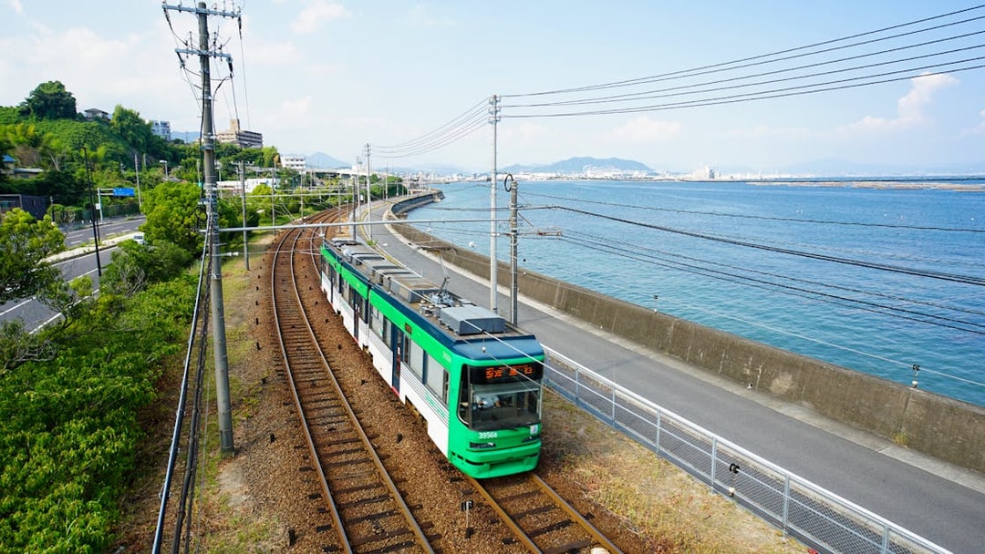 Tram traveling along the coast in Hiroshima, Japan, with ocean and cityscape views.