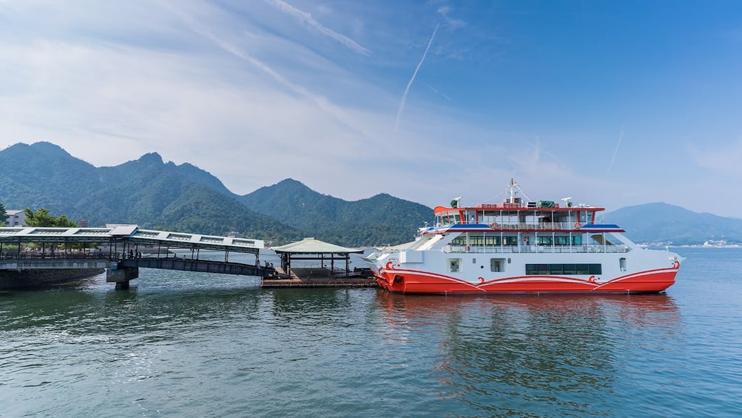 JR West Miyajima ferry docked with mountains in the background.