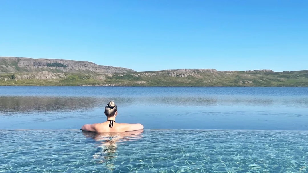 Person relaxing in Vök Baths infinity pool overlooking Lake Urriðavatn, Egilsstaðir.