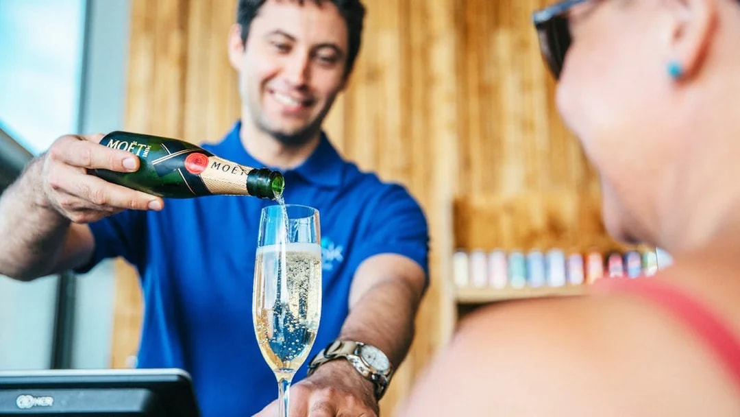 Server pouring champagne at Vök Baths bar in Egilsstaðir.