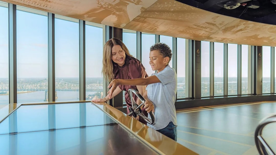 Visitors using viewfinder at Vue Orleans Observation Deck overlooking New Orleans city.