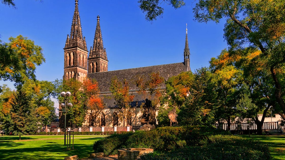 Vyšehrad Castle with twin spires surrounded by trees in Prague, Czech Republic.