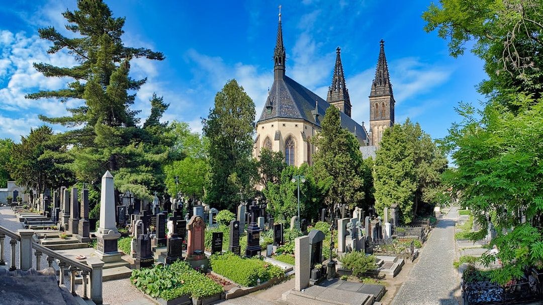 Vyšehrad Castle cemetery with church spires and surrounding greenery in Prague.