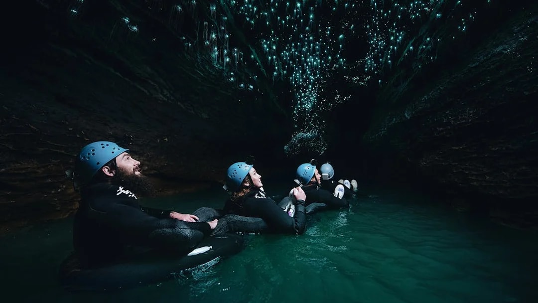Adventurers black water rafting under glowworms in Waitomo cave.