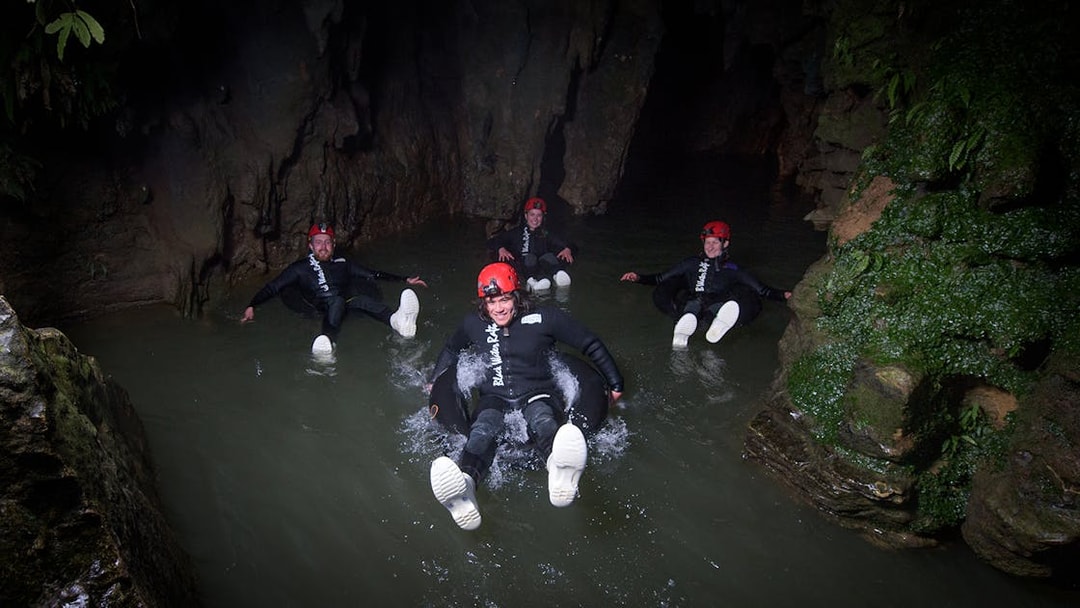 Adventurers black water rafting in a cave during a guided experience in Waitomo.