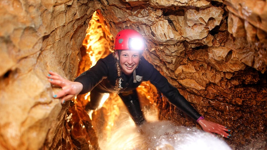 Caver exploring narrow passage during black water rafting in Waitomo cave.