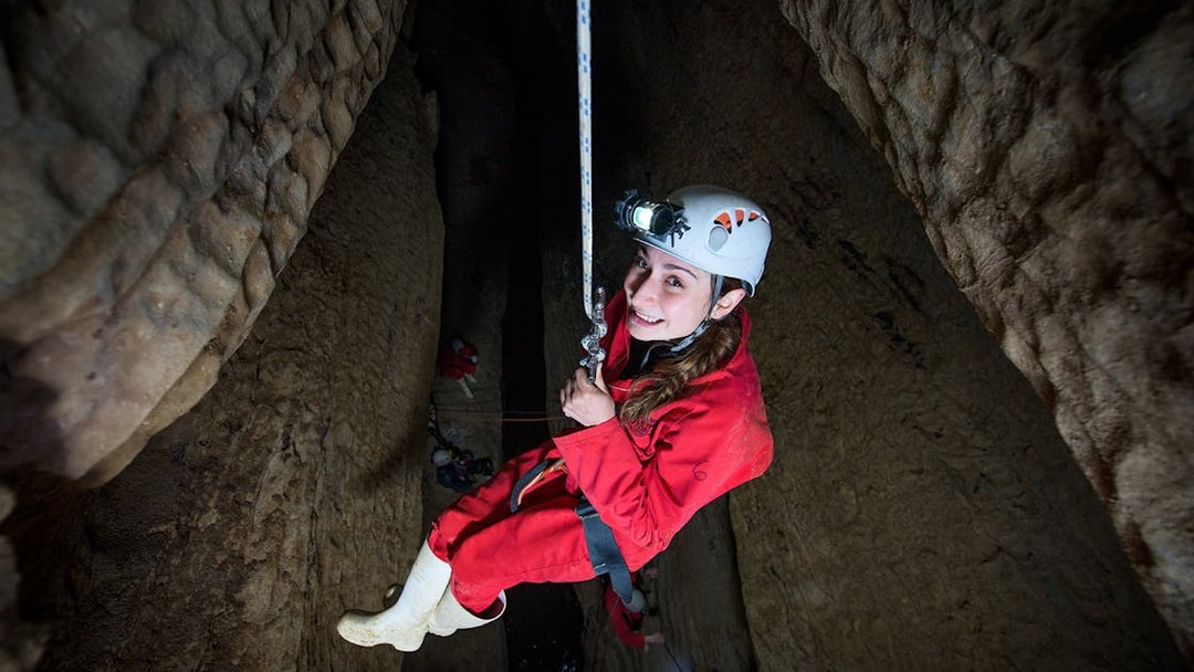 Caver descending in Waitomo cave during Black Abyss tour with zip lining and rafting.