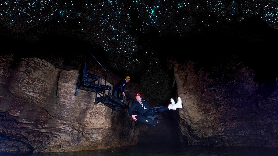 Person black water rafting under glowworms in Waitomo cave.