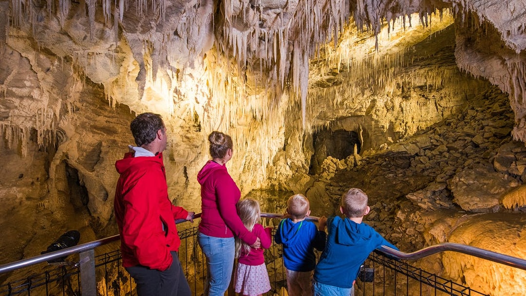 Family exploring stalactites in Waitomo Glowworm Caves, New Zealand.