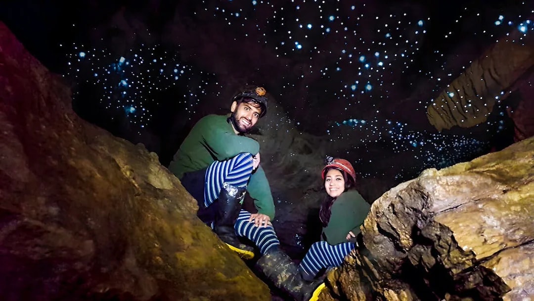 Visitors exploring Waitomo Glowworm Caves with glowing ceiling, New Zealand tour.