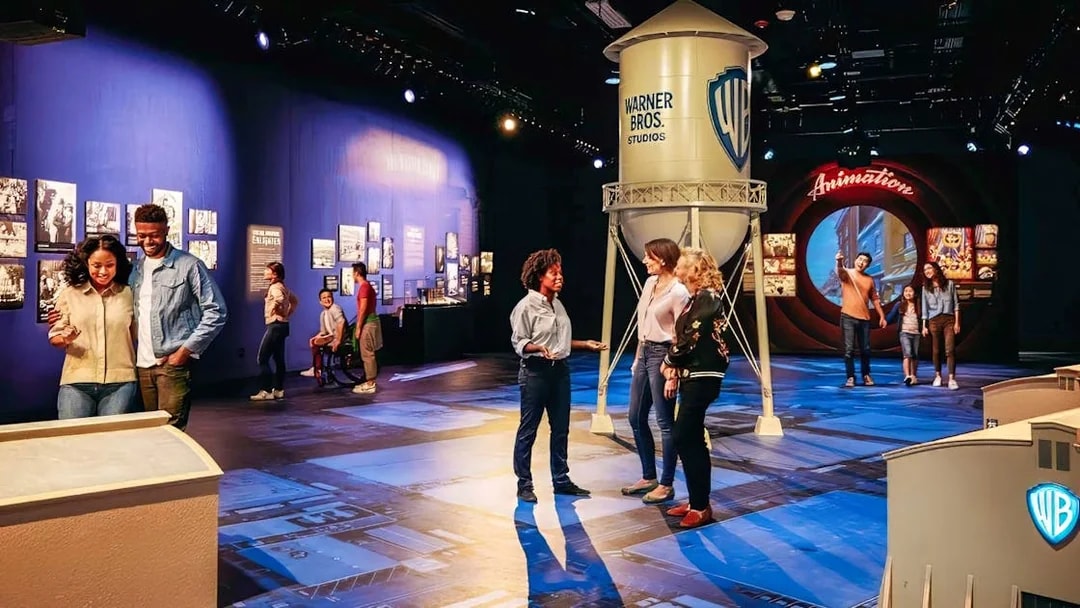 Guide leading tour at Warner Bros. Studio with visitors near iconic water tower.