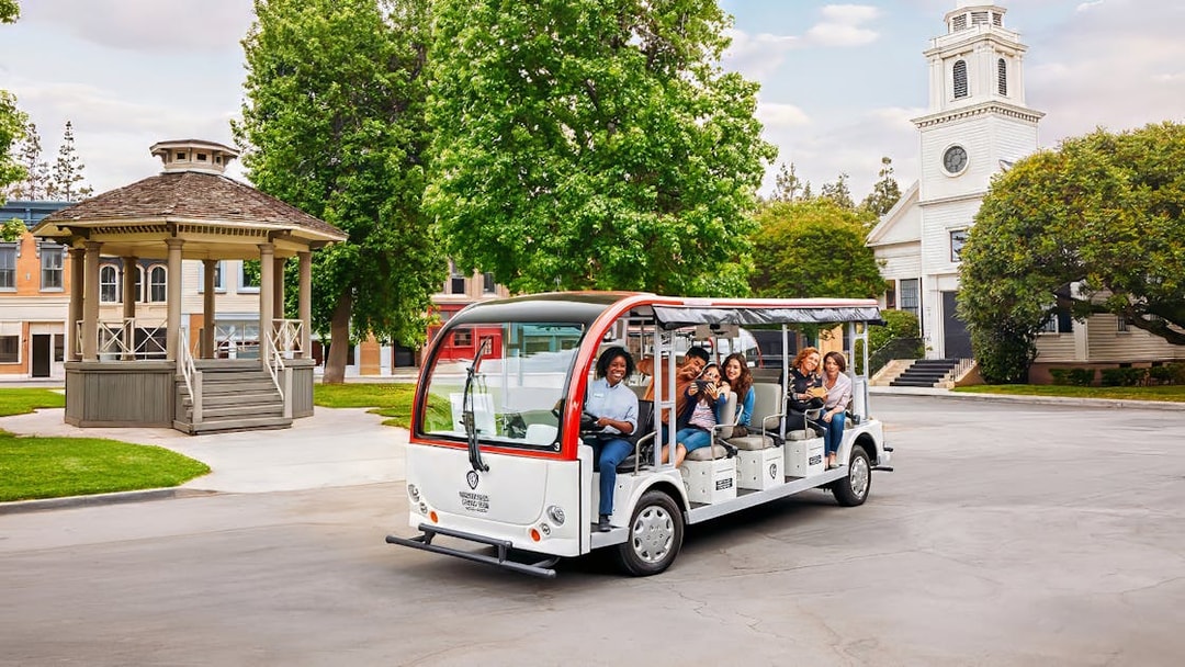 Tourists on a tram at Warner Bros. Studio, Los Angeles, with film set backdrop.