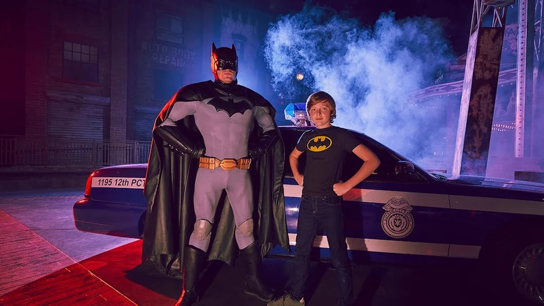 Batman character and child pose in front of police car at Warner Bros. World Abu Dhabi.