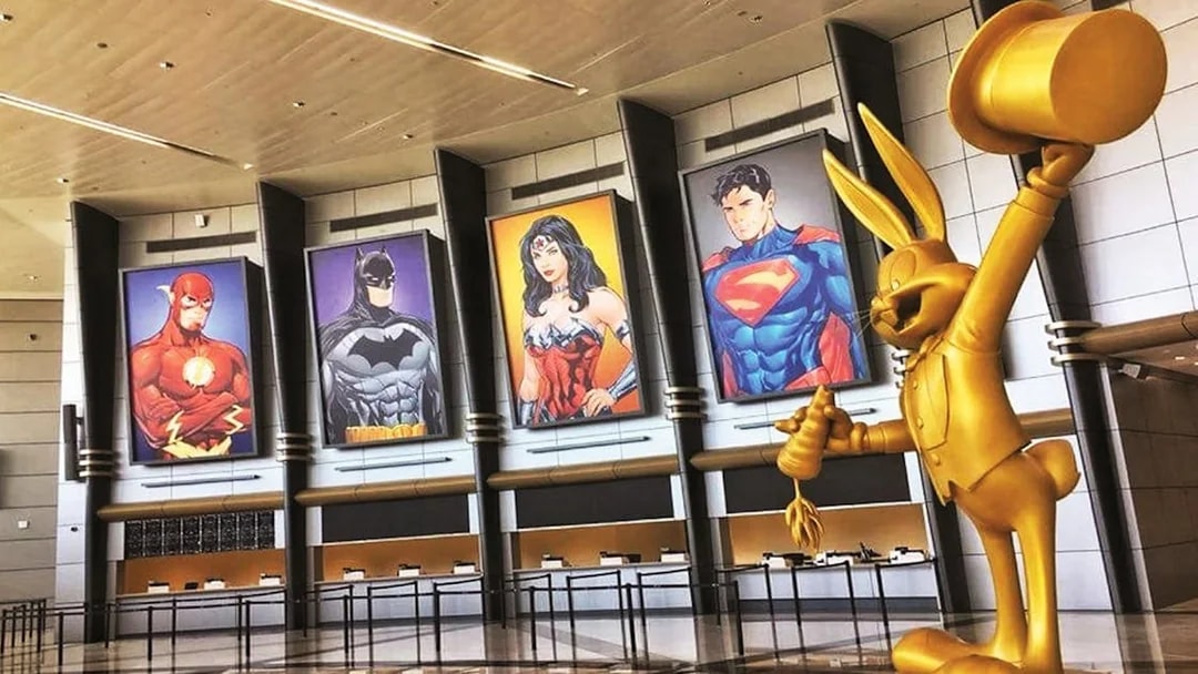 Warner Bros. World™ Abu Dhabi entrance with superhero posters and golden cartoon statue.