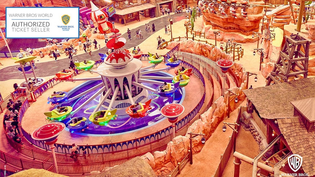 Aerial view of a colorful ride at Warner Bros. World Abu Dhabi with visitors enjoying the attraction.