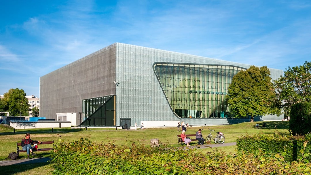 Polin Museum exterior with visitors on benches in Warsaw, Poland.