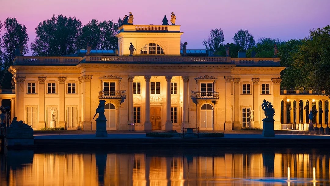 Lazienki Palace in Warsaw at sunset reflecting on the water.