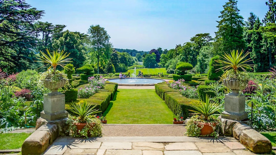 Warwick Castle gardens with fountain and manicured hedges in the background.