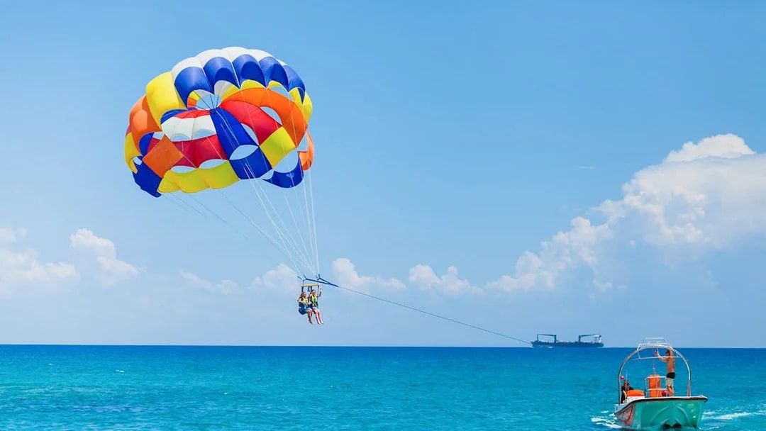 Parasailing over the ocean in Pantai Cenang with colorful parachute and boat.