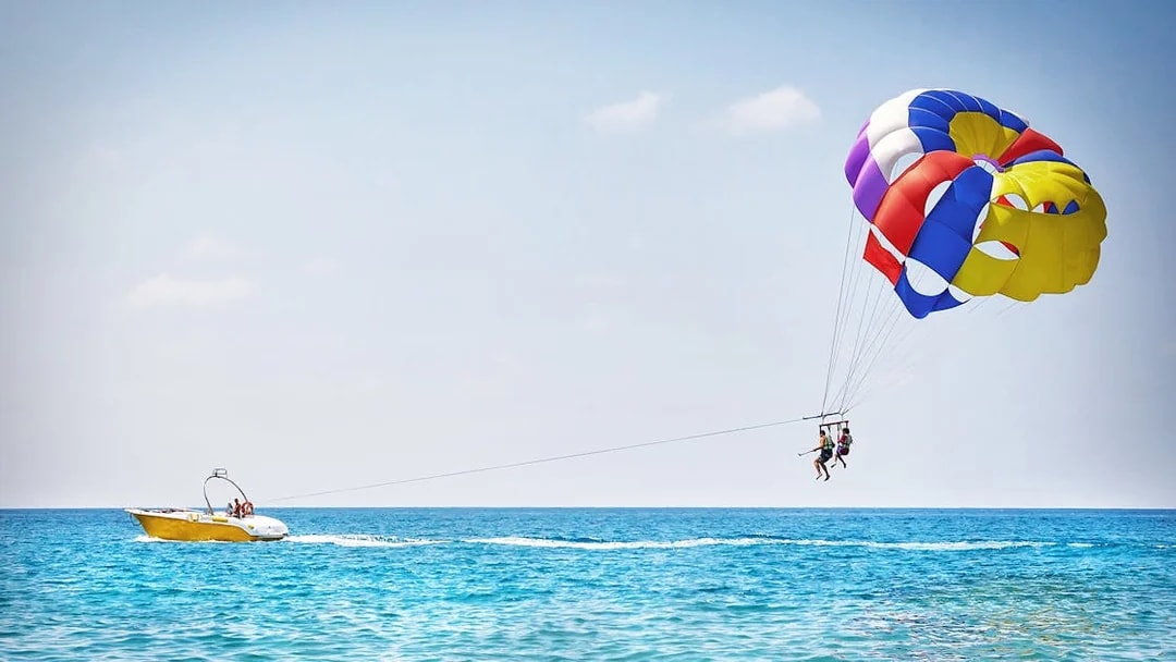 Parasailing over the ocean in Pantai Cenang with colorful parachute and speedboat.