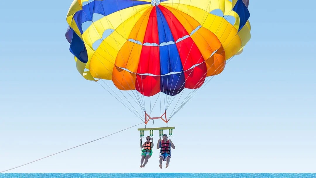 Parasailing over the ocean in Pantai Cenang with colorful parachute.