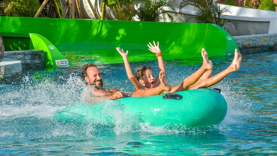 Father and son enjoying a water slide on a tube at Waterbom Bali water park.