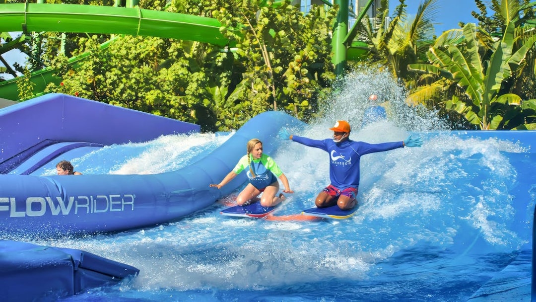 Instructor guiding a girl on a surfboard at Flow Rider, Waterbom Bali water park.