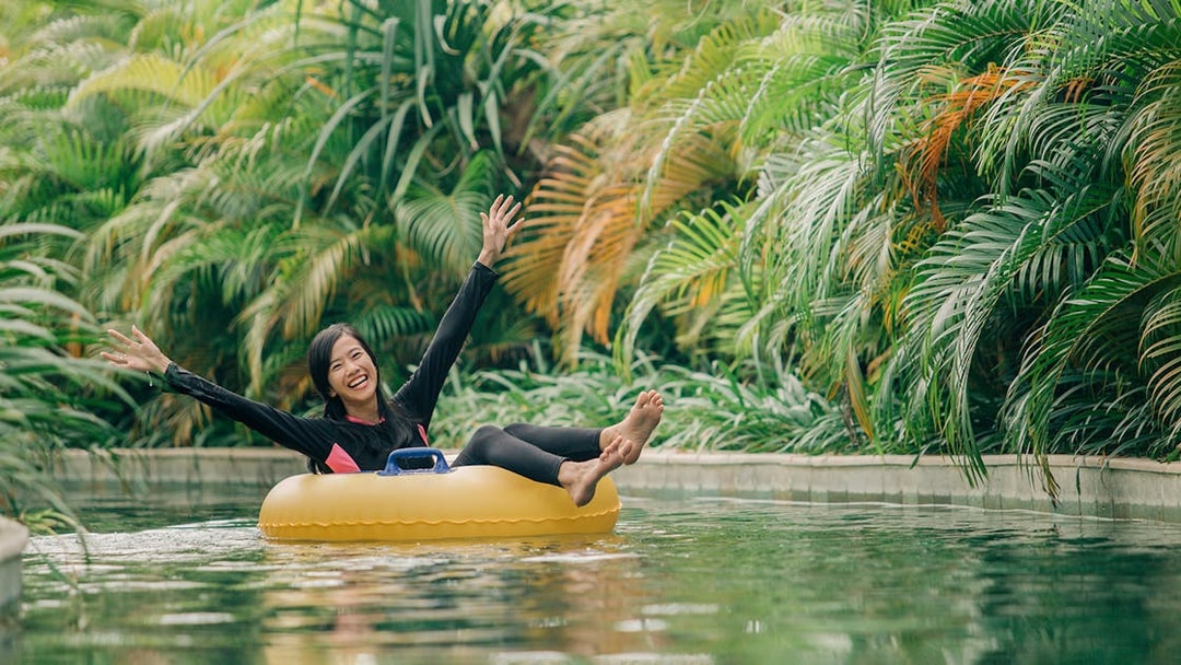 Girl floating on a ring in lazy river at Waterbom Bali surrounded by lush greenery.