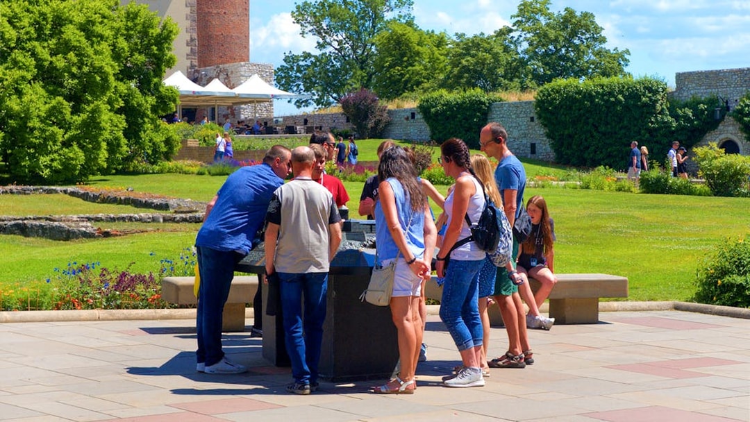 Tourists examining a miniature model of Wawel Royal Castle in a garden setting.