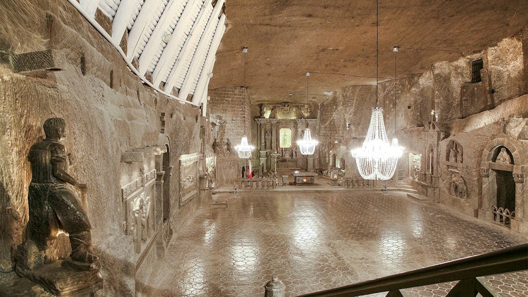 Wieliczka Salt Mine chapel with chandeliers and carved salt statues.