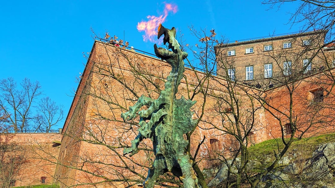 Wawel Dragon statue breathing fire near Wawel Castle walls in Krakow, Poland.