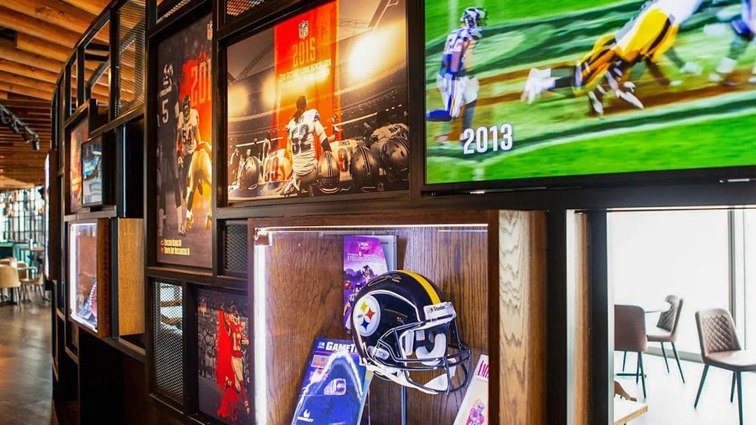 NFL memorabilia display at Wembley Stadium gallery featuring helmets and game footage.