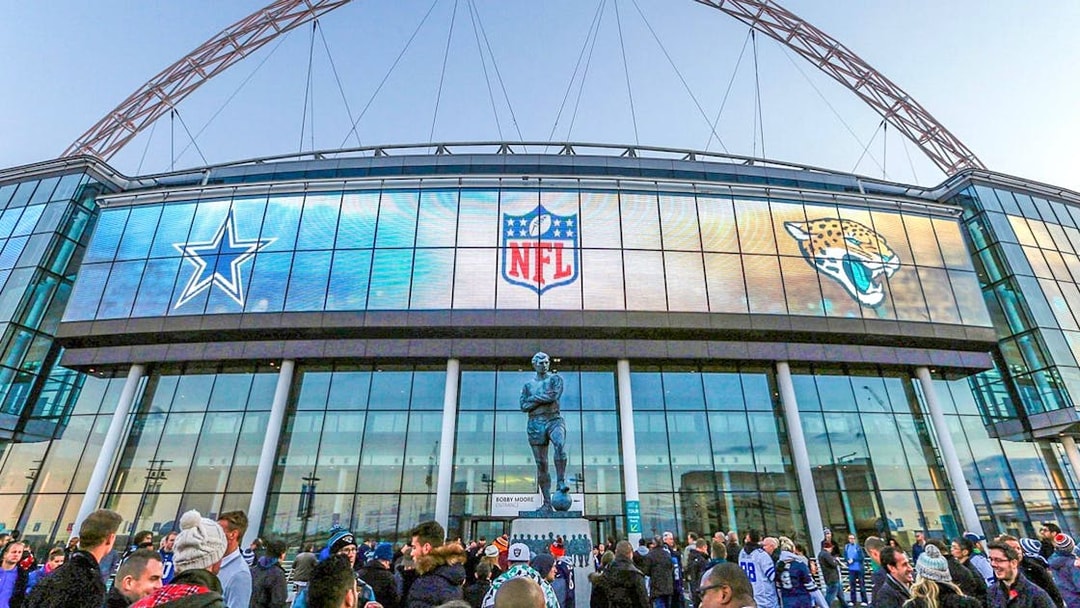 Wembley Stadium exterior with NFL logos and crowd gathering.