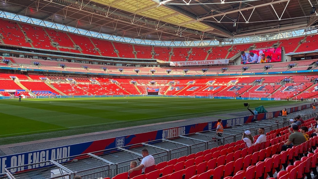 Wembley Stadium interior with red seats and green pitch, London.