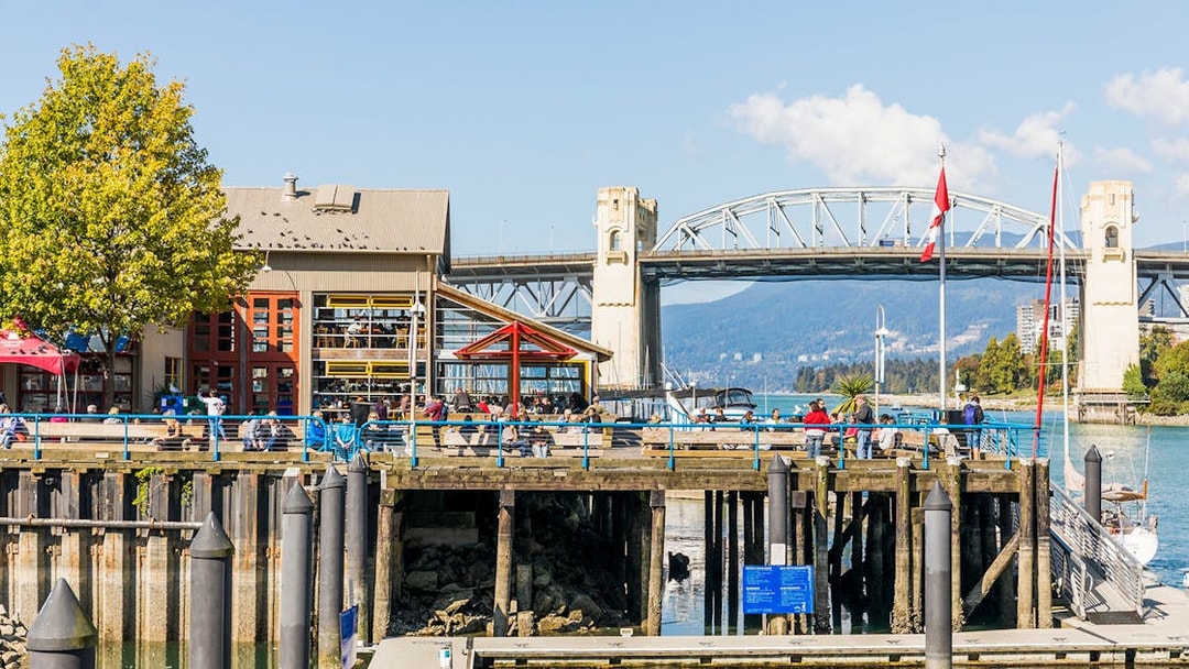 Burrard Street Bridge in Vancouver with waterfront view and people on a pier.