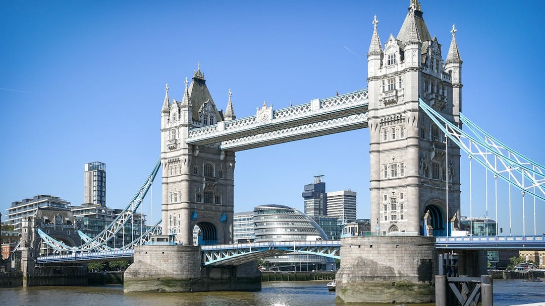 Tower Bridge spanning the River Thames in London with modern buildings in the background.