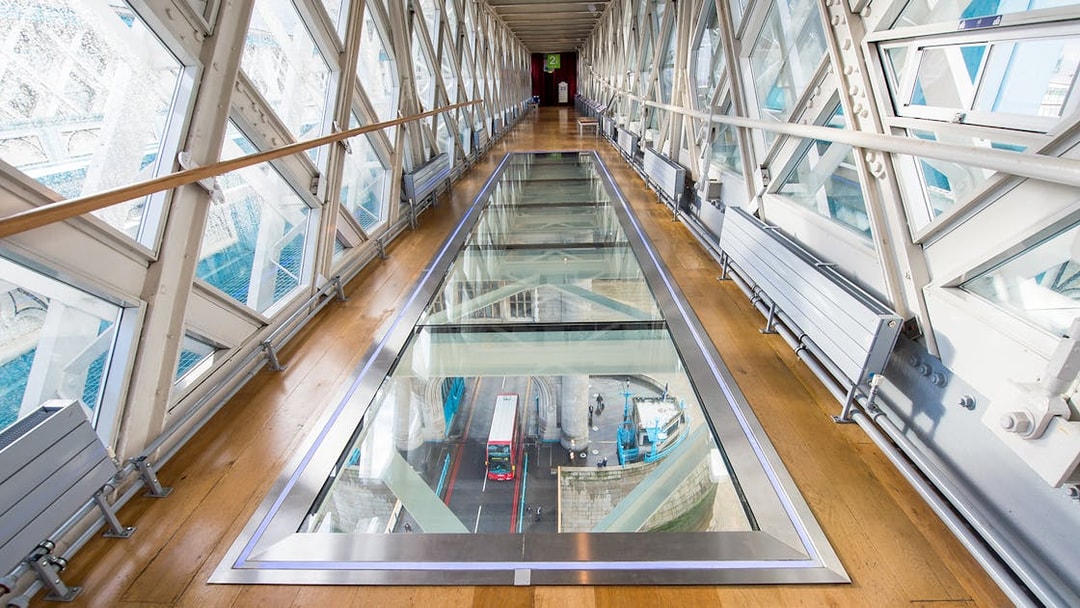 Glass walkway inside Tower Bridge with view of London bus below.