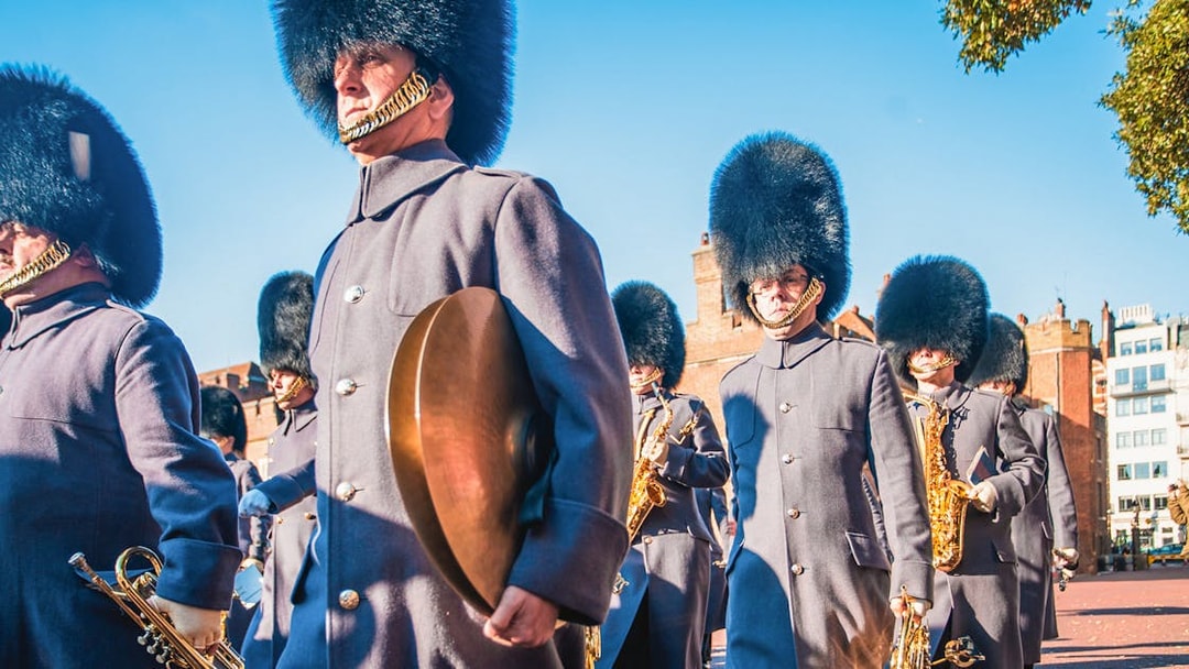 Royal guards in traditional uniforms marching near Tower Bridge, London.