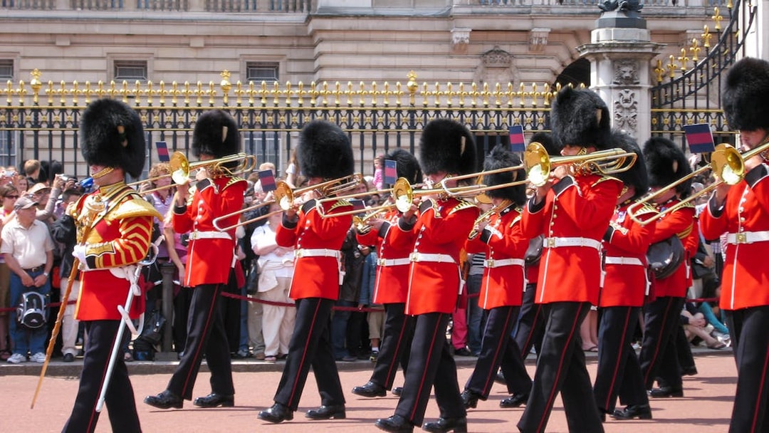 Guards in red uniforms and bearskin hats perform at Changing of the Guard, London.