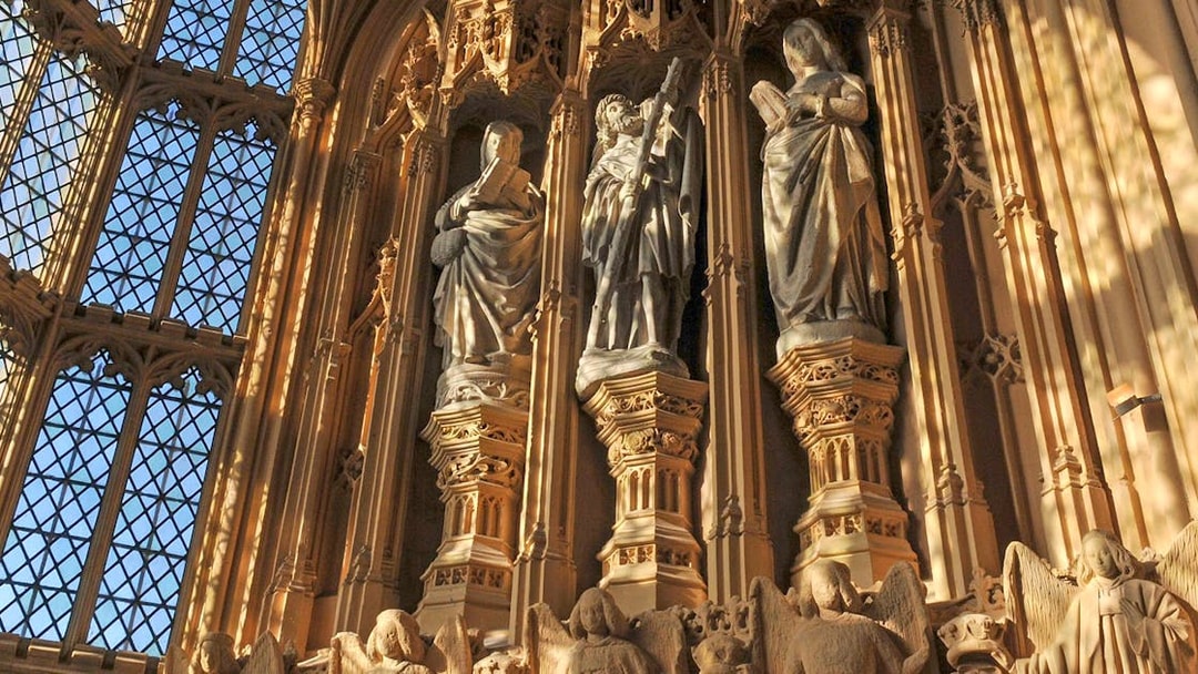 Statues inside Westminster Abbey, London, with intricate carvings and stained glass windows.
