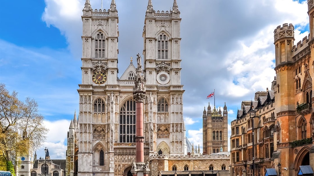 Westminster Abbey facade with clock tower and surrounding buildings, London.