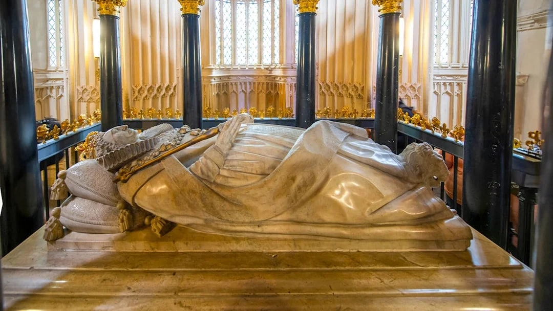 Tomb inside Westminster Abbey with ornate columns and detailed carvings.